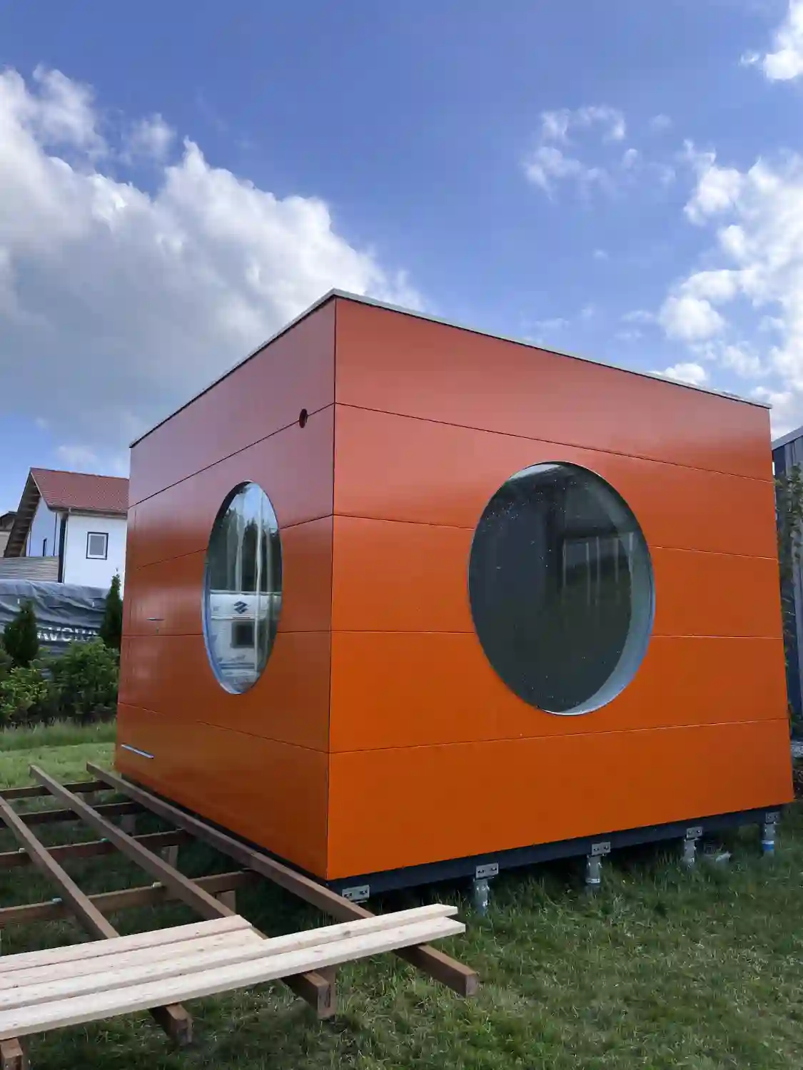 Orange gestrichenes modernes Gartenbüro mit Flachdach und Rundfenstern auf Krinner Schraubfundamente montiert
