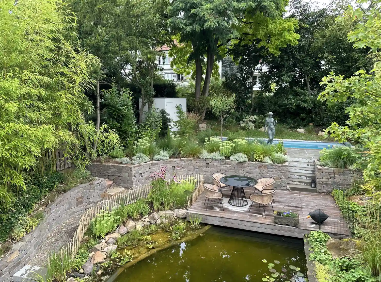 Blick von oben auf perfekt designten Garten mit Pflanzen, Teich, Pool, Terrasse und farblich angepasstem Design-Gartenhaus
