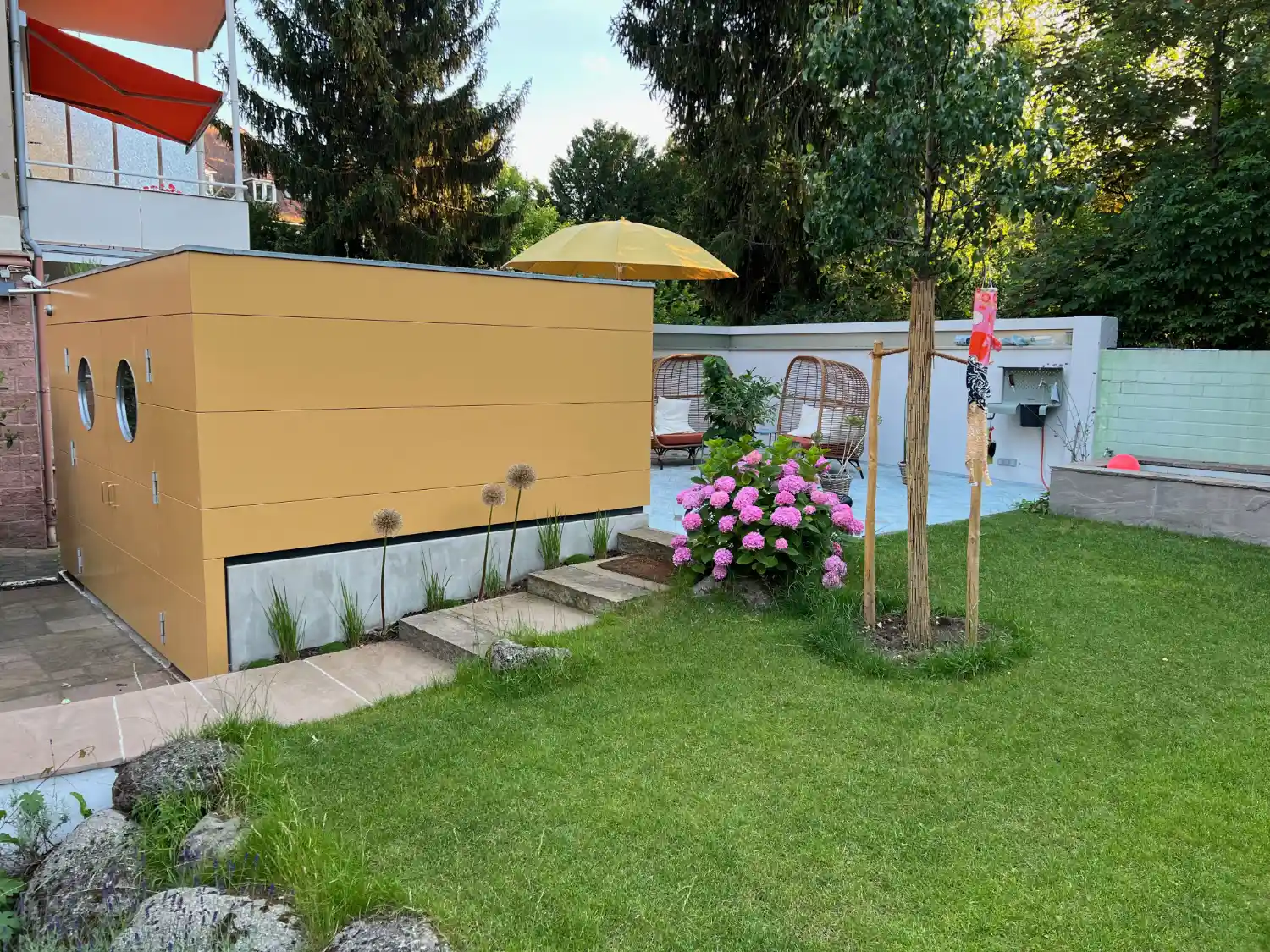 Gartenhaus mit Flachdach und ockerfarbener Fassade, gebaut auf Betonfundament zum Ausgleich verschiedener Hoehenniveaus