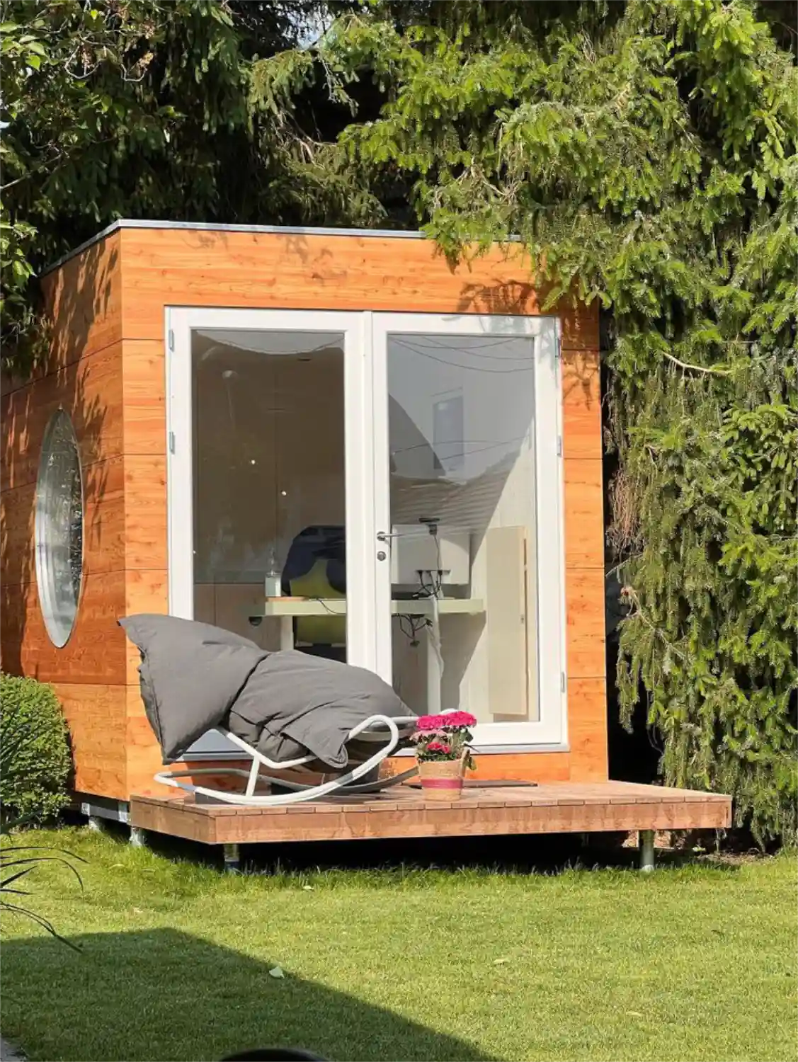 Office Kubus mit Lärche-Fassade auf Krinner-Schraubfundamenten in engem Gartenbereich zwischen Bäumen