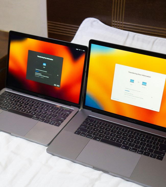 two laptops on a bed