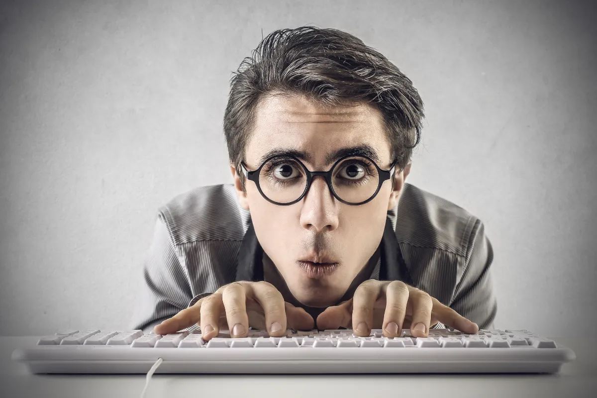 a man wearing glasses and typing on a keyboard