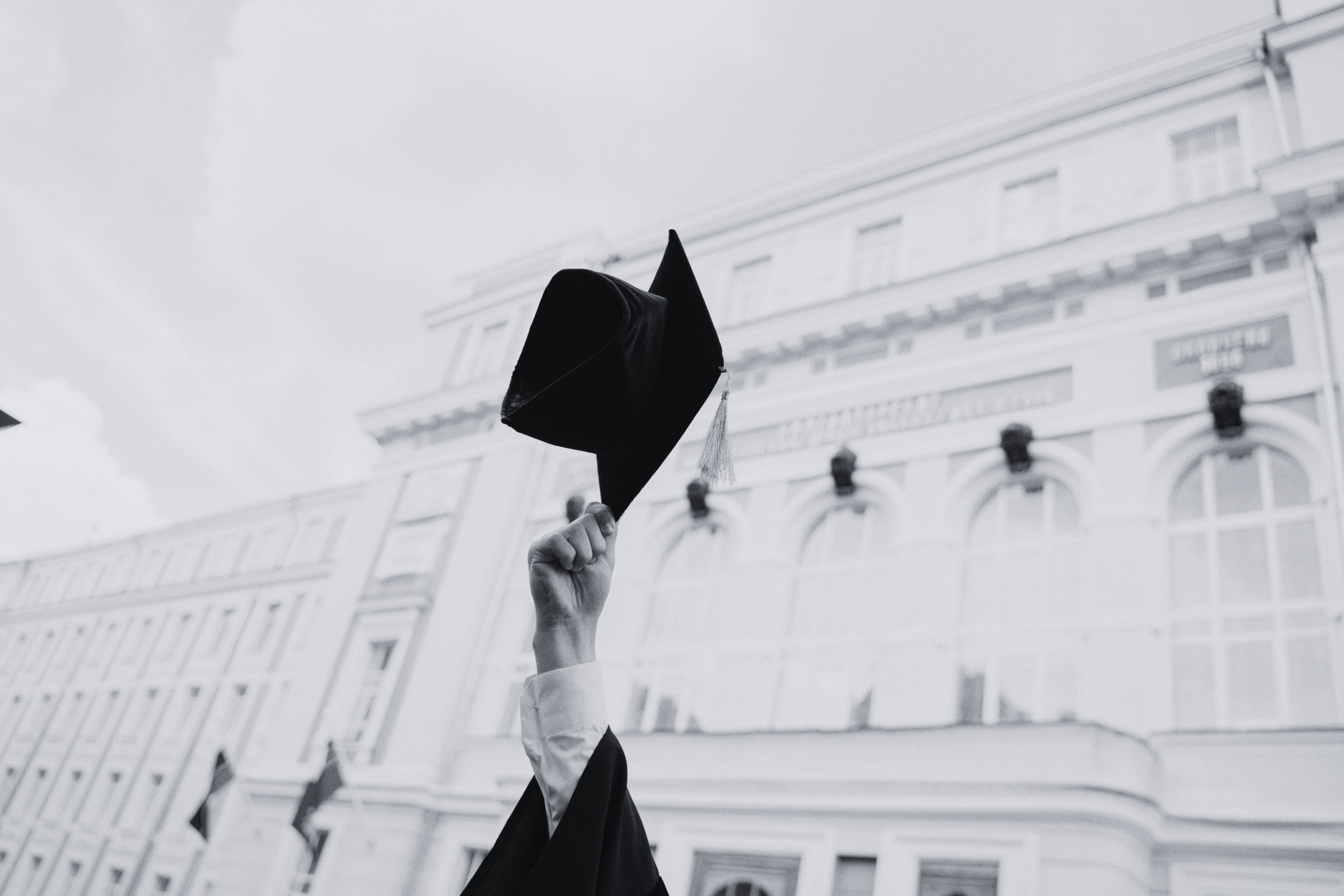 Architecture graduate holding a graduation cap in front of a classical building