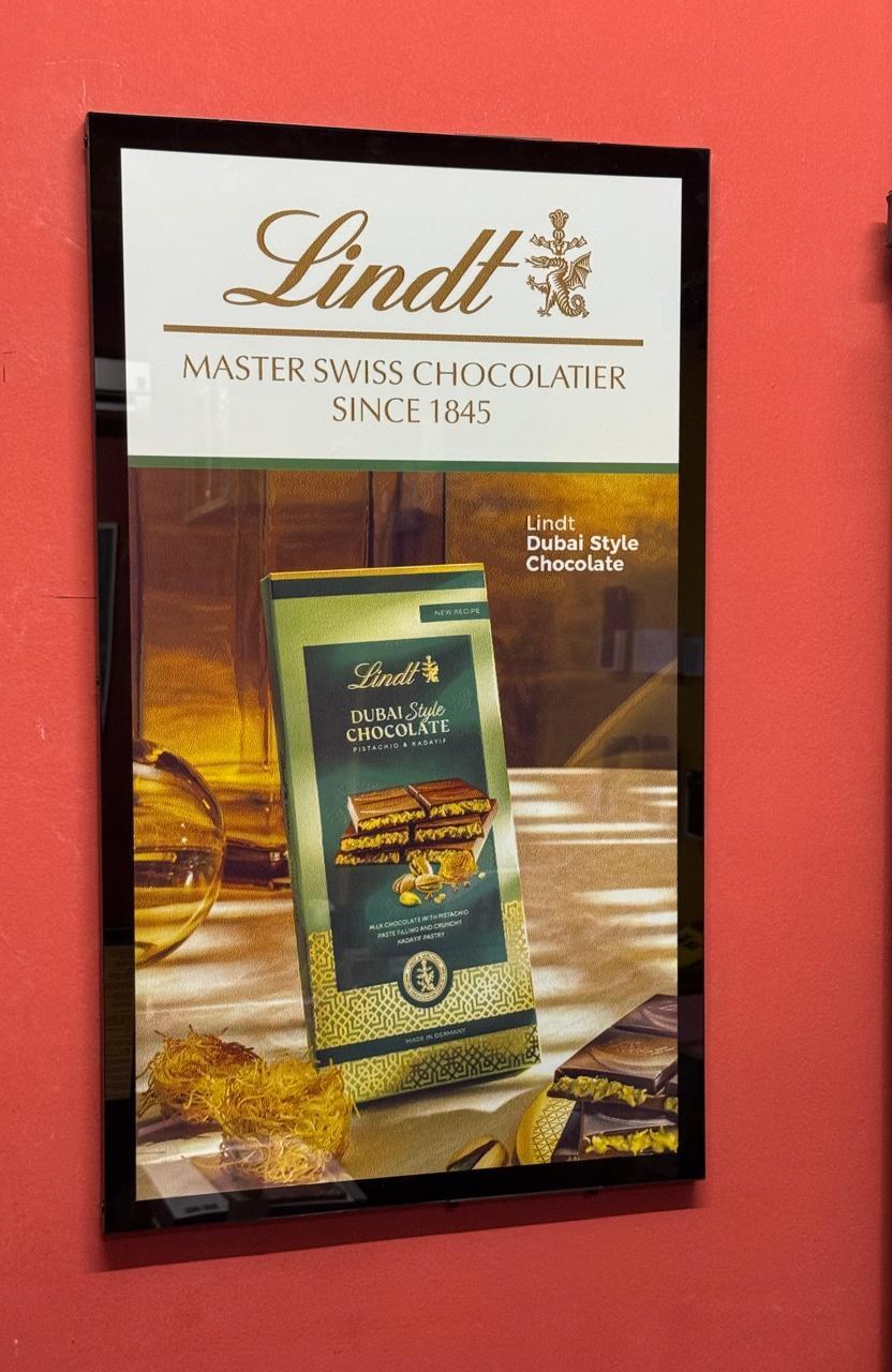 Wall-mounted onQ ePoster e-paper display in a retail environment by onQ Digital