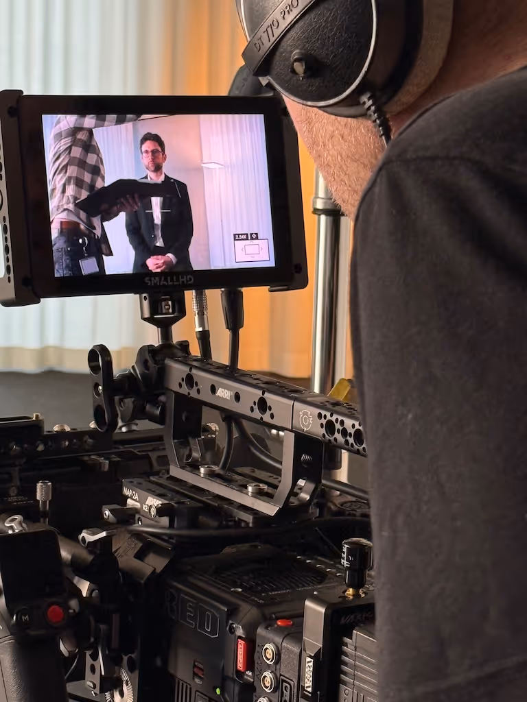 Videokamera auf Dolly im Aufnahmebereich mit drei Personen vor einer Kuka-Wandkarte in einem Studio.