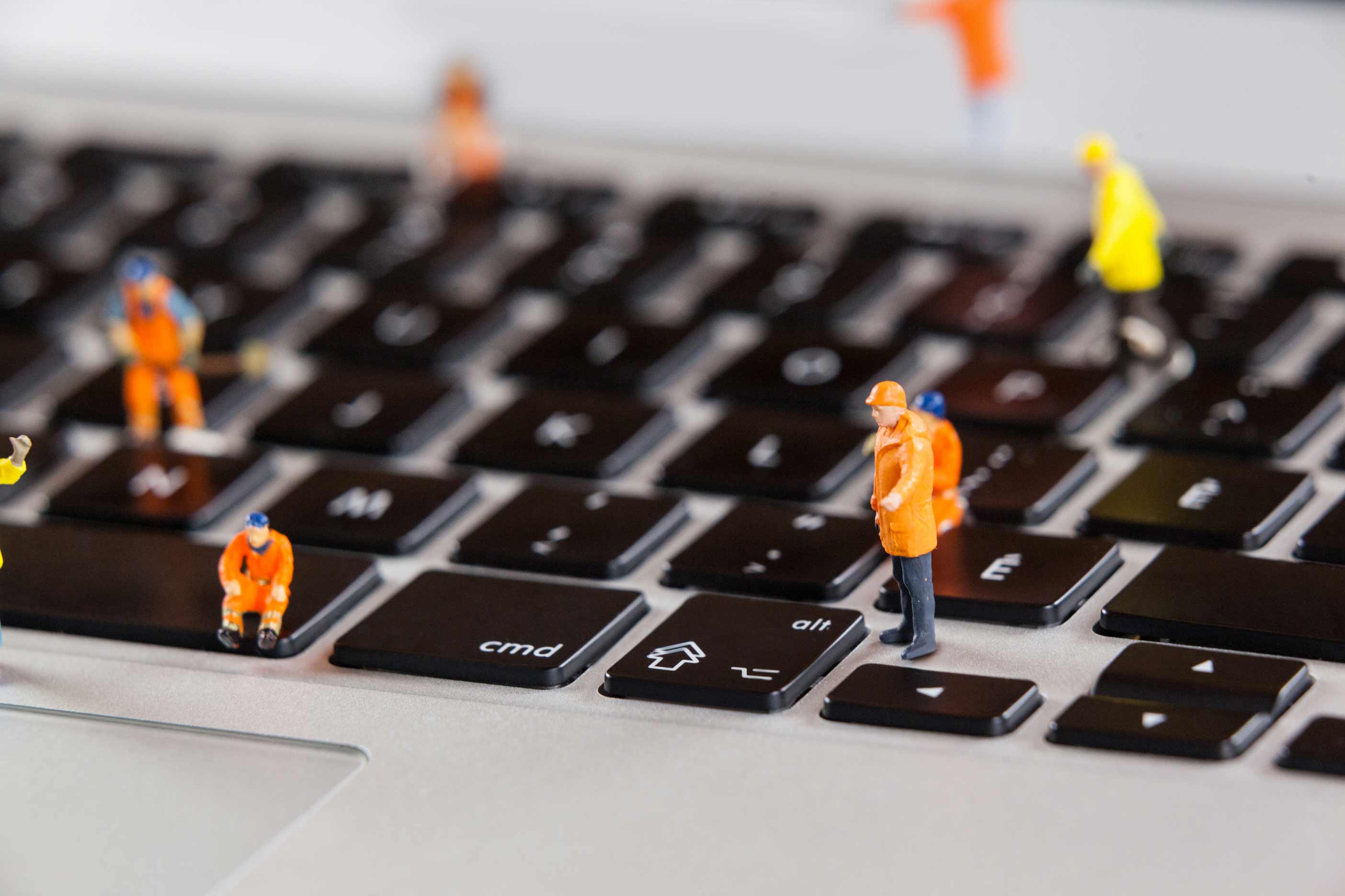 Miniature workmen repairing laptop keyboard