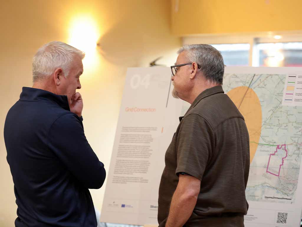 Two people in conversation after reviewing an info-graphic displayed on an easel 
