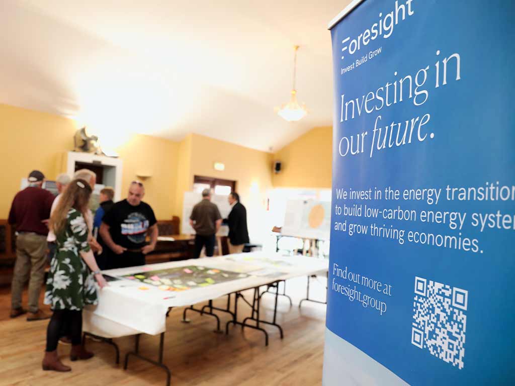 A group of people are reviewing large info-graphics displayed on a table