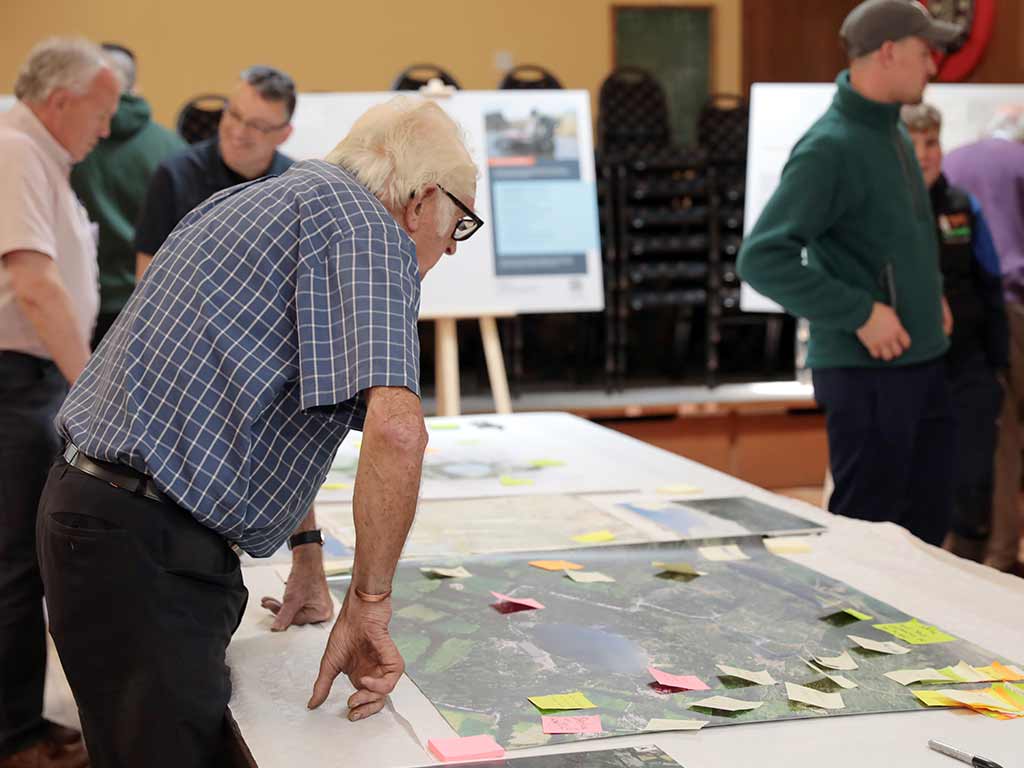 A man leans over a table to get a closer look at an info-graphic