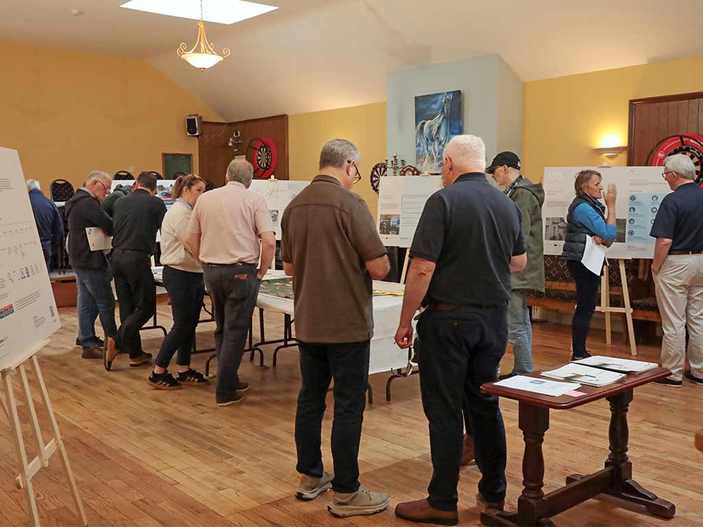 A group of people are reviewing large info-graphics displayed on a table