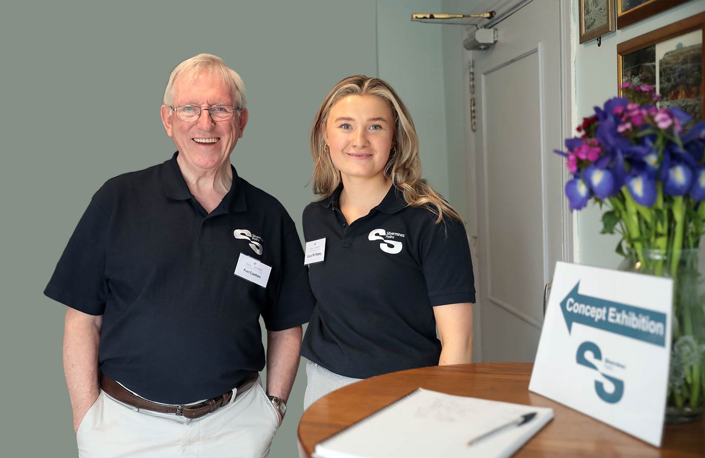 A man and a woman stand smiling wearing black shirts with Skermines Hydro logos and name tags.