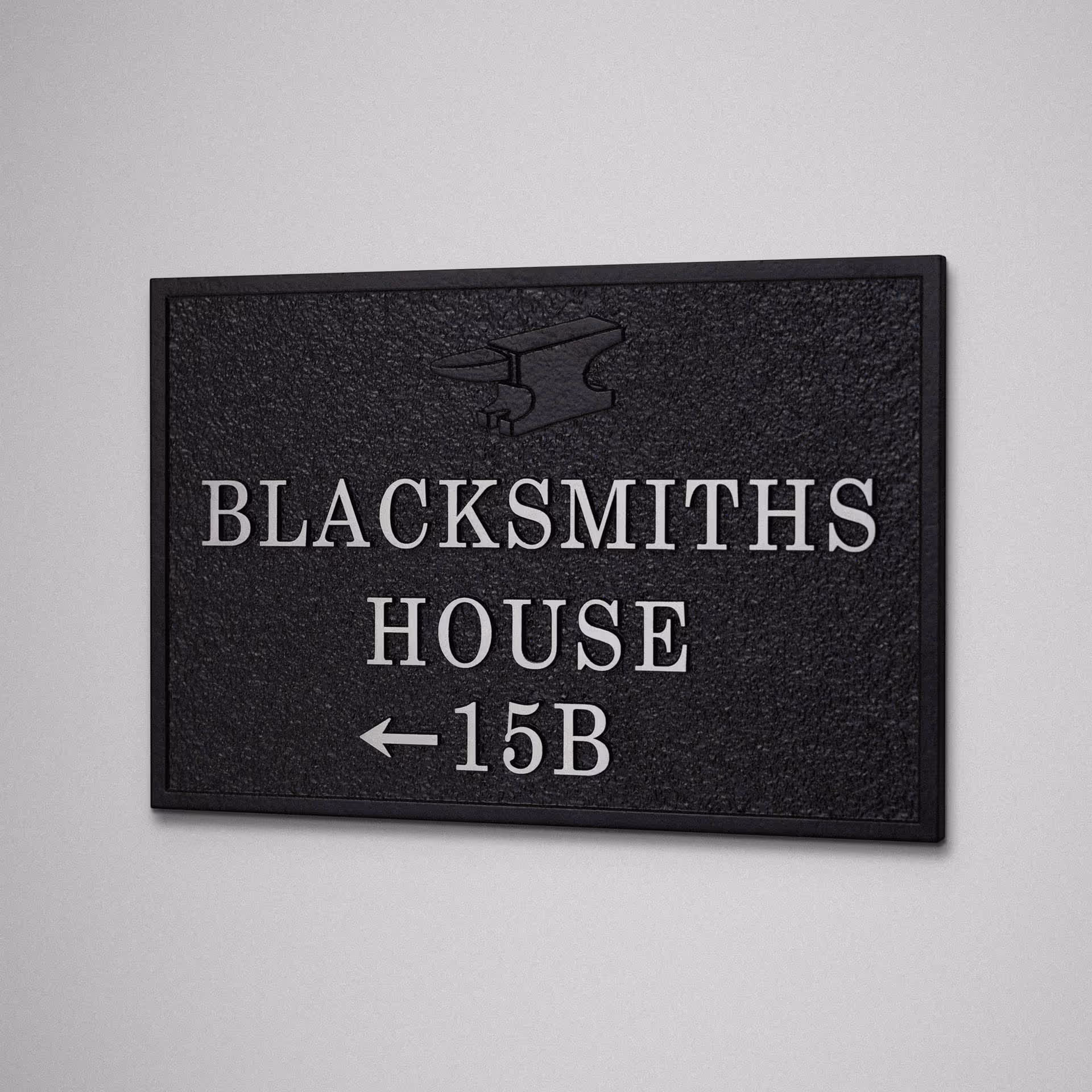 Cast aluminium house sign for Blacksmiths House with serif lettering, arrow and subtle anvil motif.