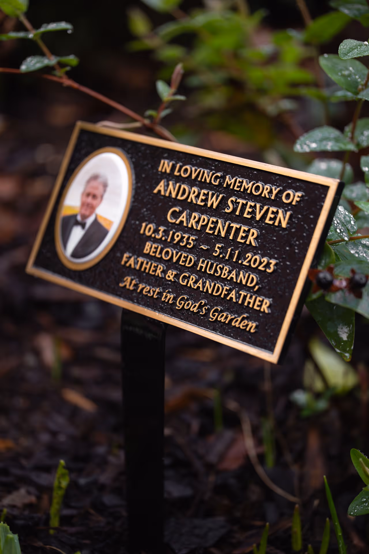 Angled view of a cast memorial plaque with raised lettering and photo cameo on a ground stake.