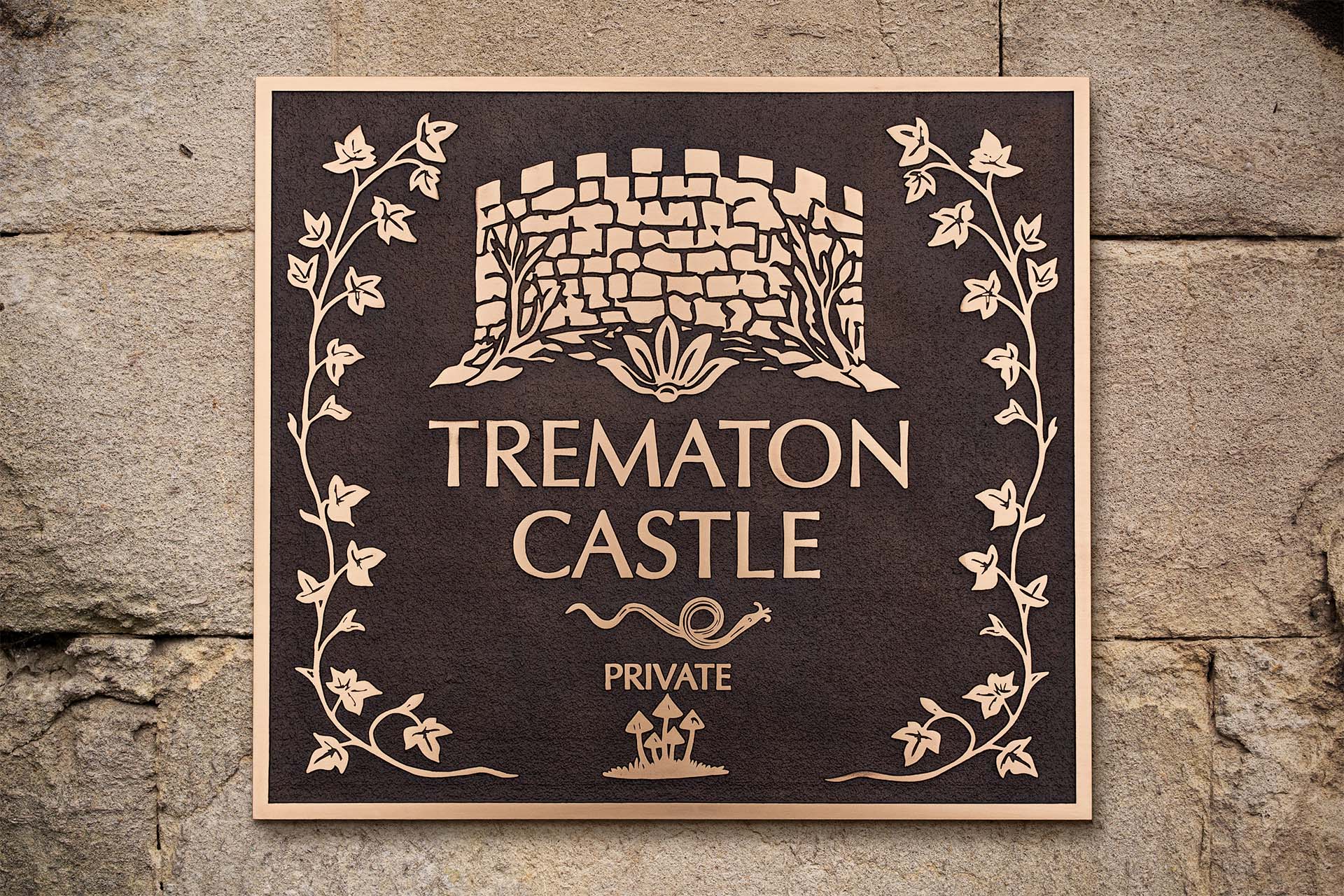 Cast bronze plaque for Trematon Castle with raised text and artwork, featuring a stylised stone battlement, ivy border, and engraved 'Private' notice. Elegant design on a textured brown background, ideal for historic or luxury property signage.