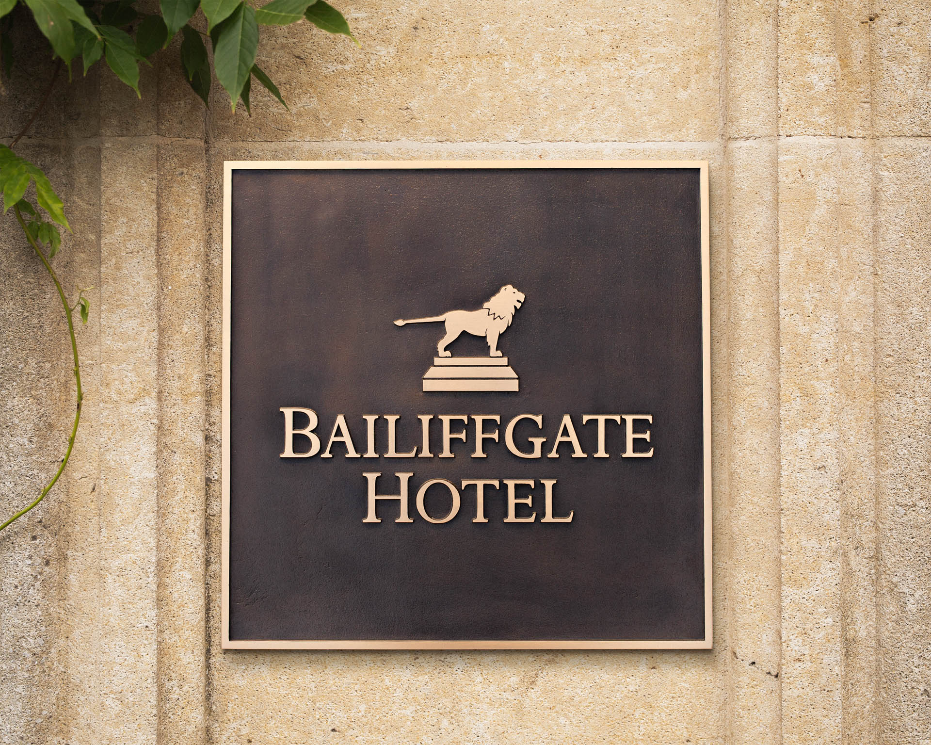 18x18 inch custom cast bronze hotel sign for Bailiffgate Hotel, featuring a naturally patinated background and linished gold lettering with a raised lion emblem — premium handcrafted signage by Anglia Sign Casting.