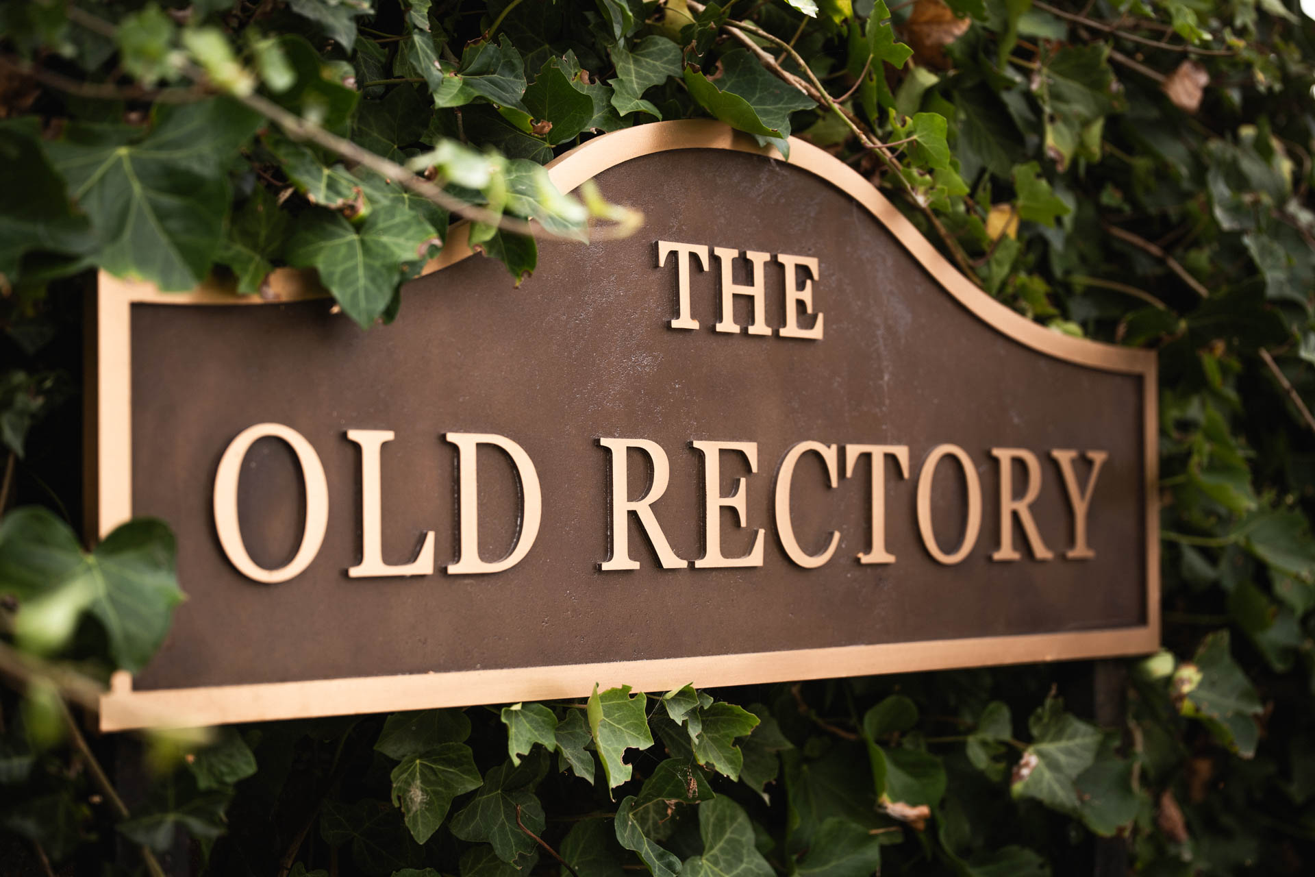 Large handcrafted metal house sign reading 'The Old Rectory' in raised bronze lettering with a curved top, made by Anglia Sign Casting.