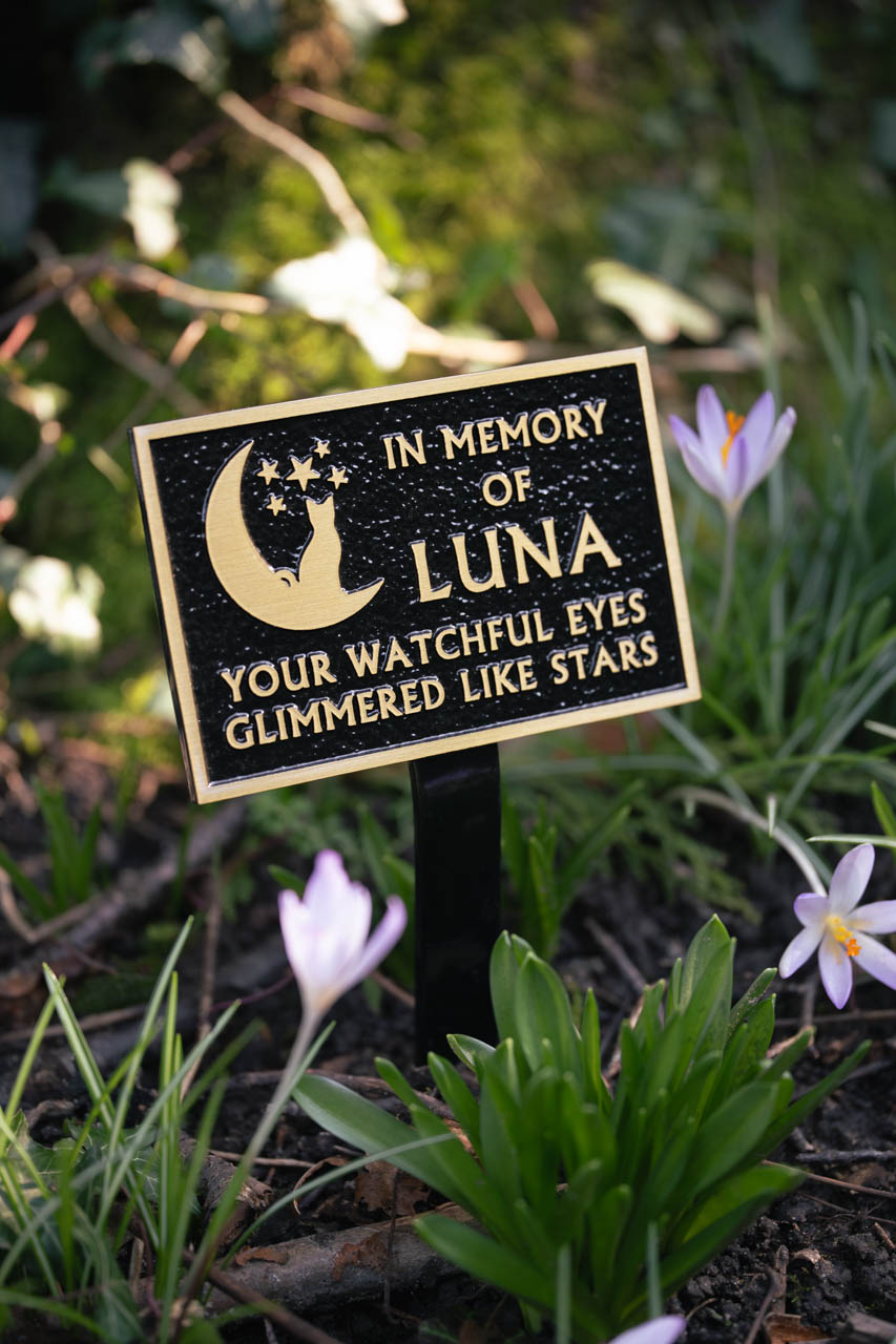 Beautiful cast bronze pet memorial plaque with a black textured background, featuring an integral ground stake for secure outdoor placement. Personalised with a unique moon and stars cat motif and raised gold lettering, this bespoke plaque offers a heartfelt tribute to a beloved pet. Weather-resistant and durable, perfect for gardens, pet cemeteries, and memorial spaces, providing a lasting and elegant remembrance.
