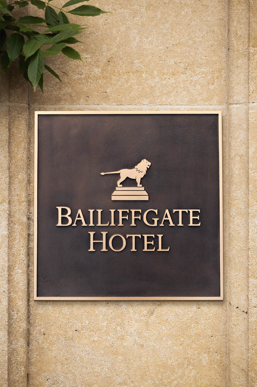 Large custom cast bronze hotel sign for Bailiffgate Hotel, featuring a naturally patinated background and linished gold lettering with a raised lion emblem — premium handcrafted signage by Anglia Sign Casting.