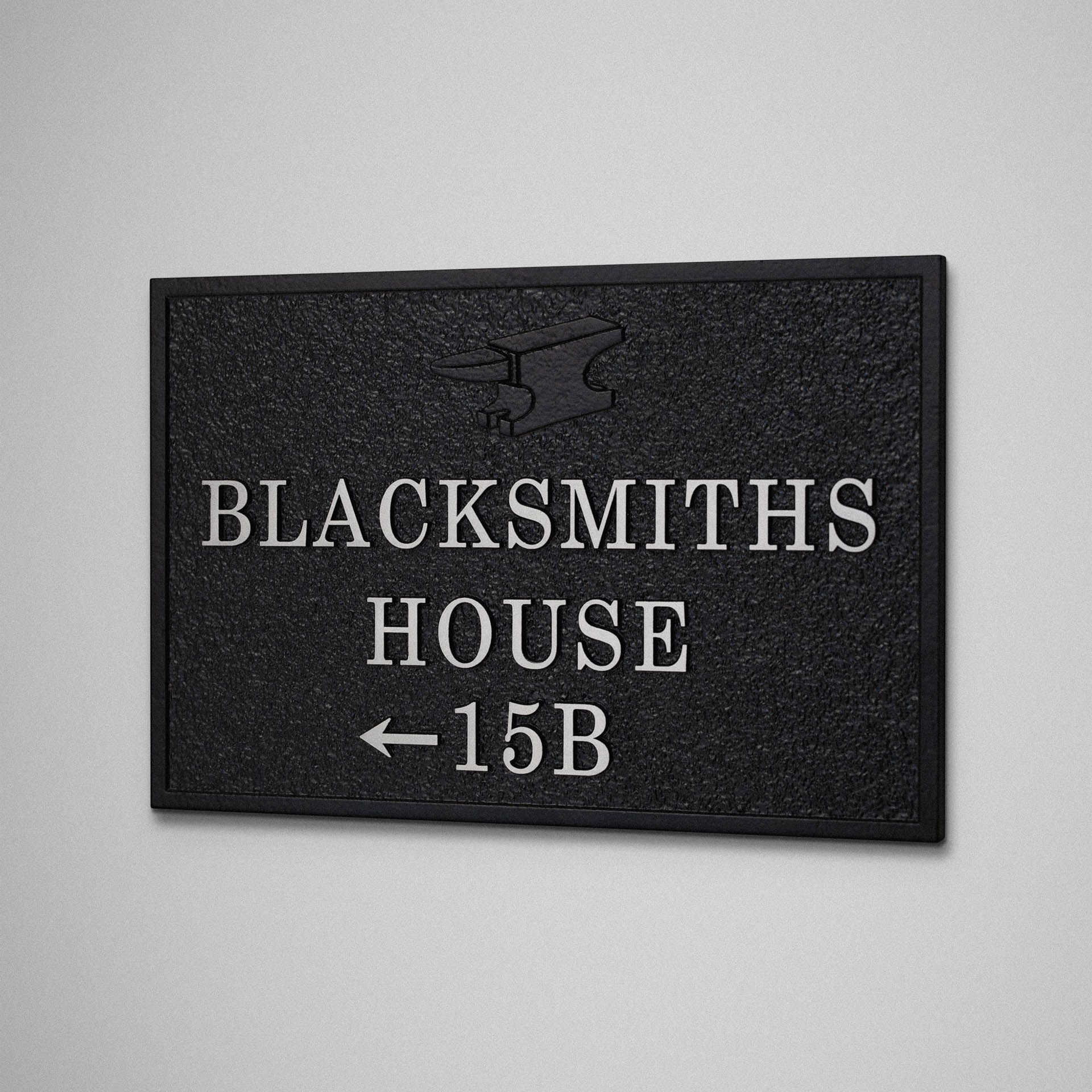 Cast aluminium house sign for Blacksmiths House with serif lettering, arrow and subtle anvil motif.