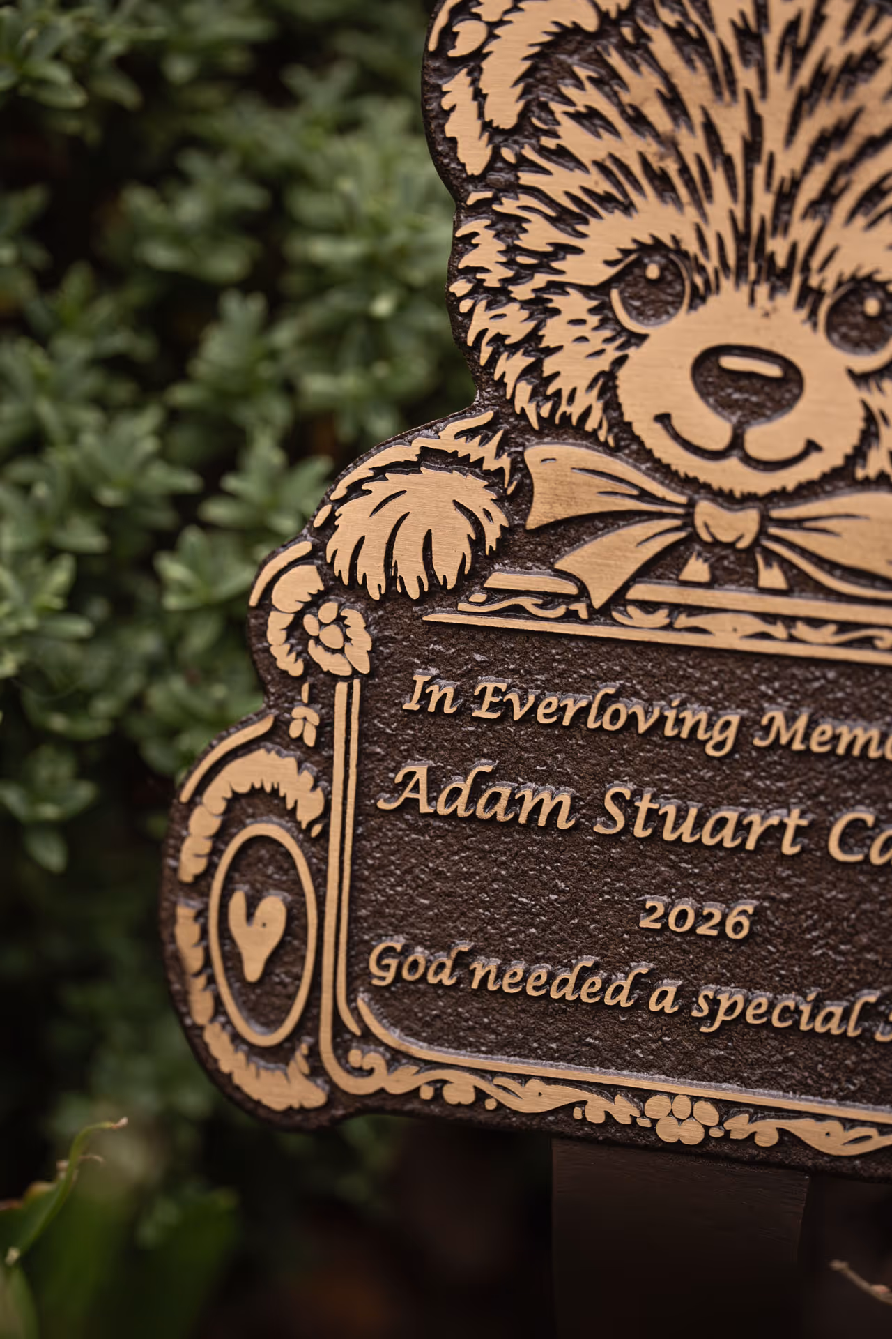 Detailed view of a teddy bear-shaped memorial plaque with raised text, suitable for remembrance gardens.