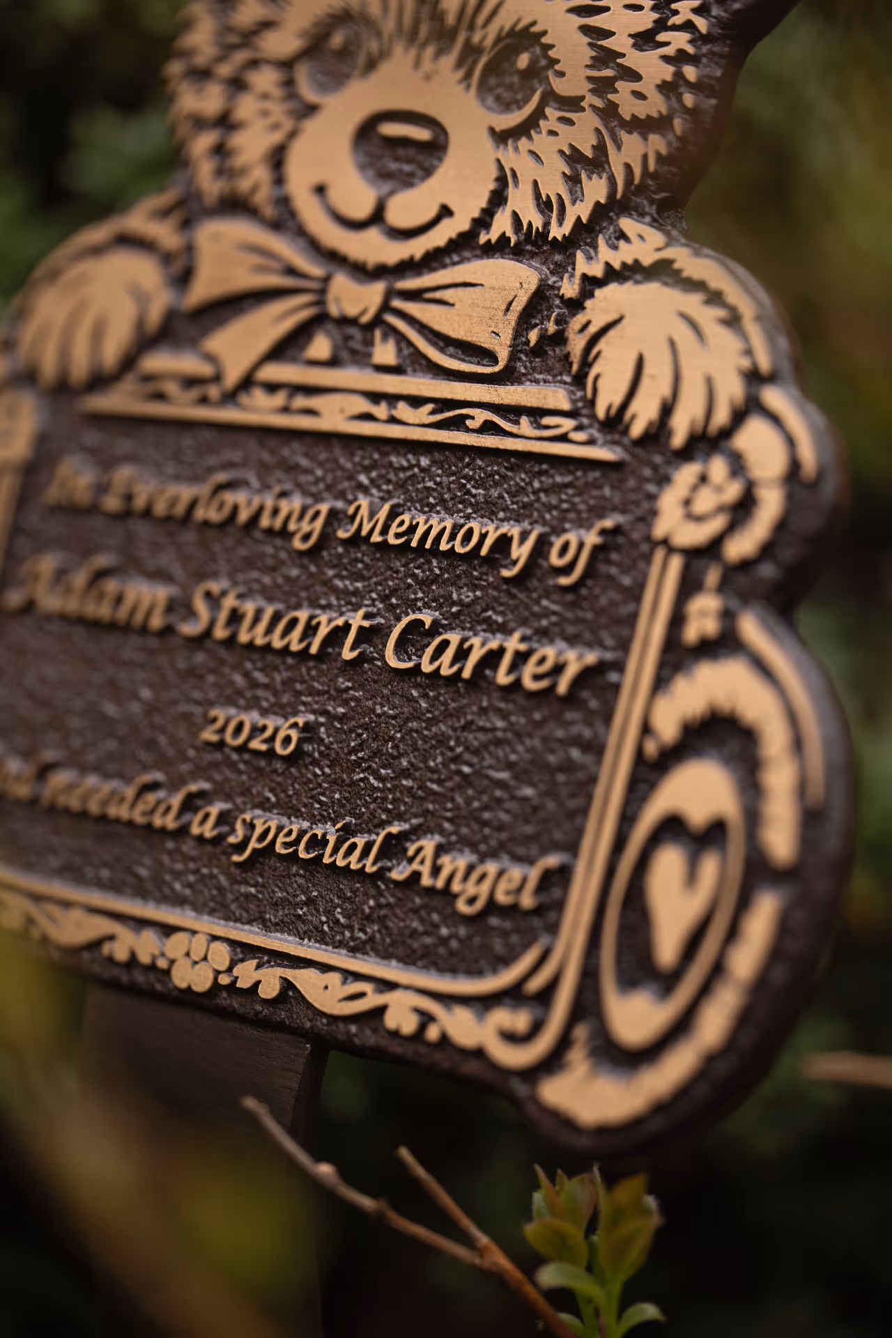Detailed view of a teddy bear-shaped memorial plaque with raised text, suitable for remembrance gardens.