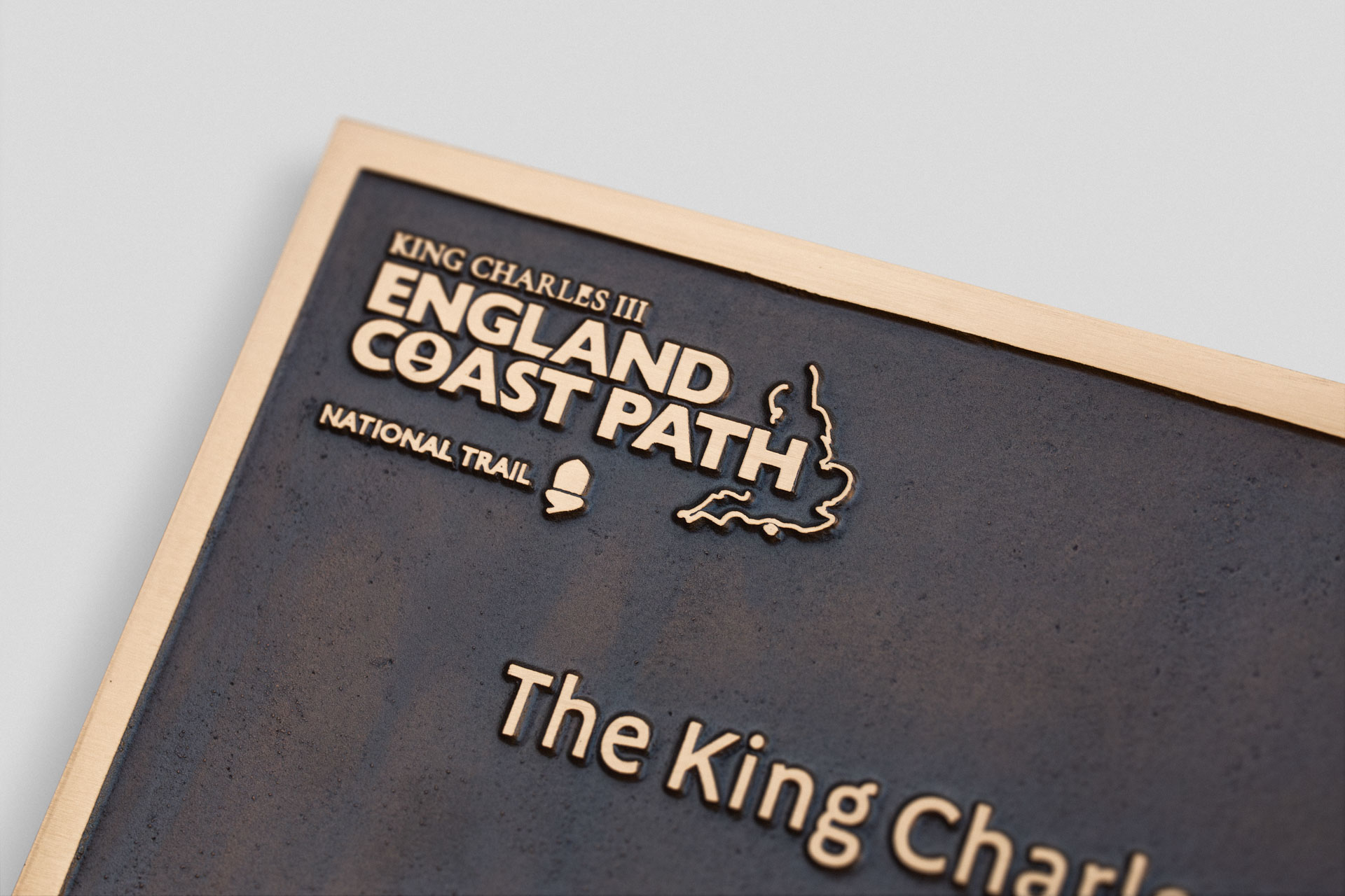 Bronze commemorative plaque showing King Charles III England Coast Path logo and lettering