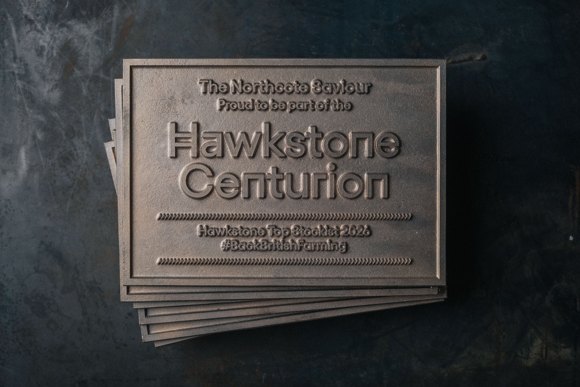 Raw bronze Hawkstone Centurion stockist plaque stacked in workshop setting as part of bespoke plaque manufacturing process.