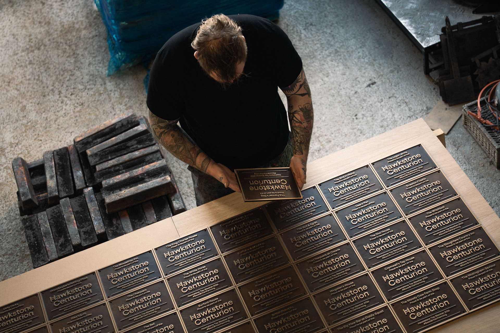 Overhead view of handcrafted Hawkstone Centurion bronze plaques being inspected in the workshop during production and finishing.