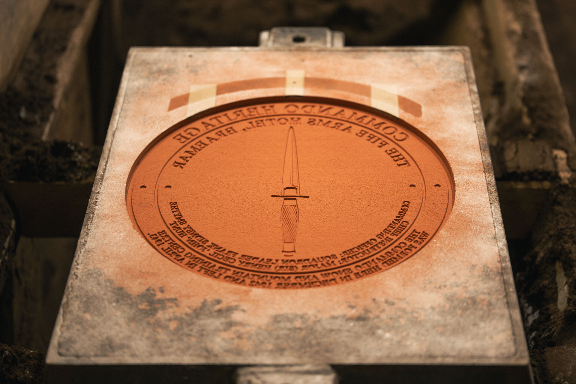 Open sand mould prepared for bronze casting in a traditional foundry workshop before molten metal pouring.