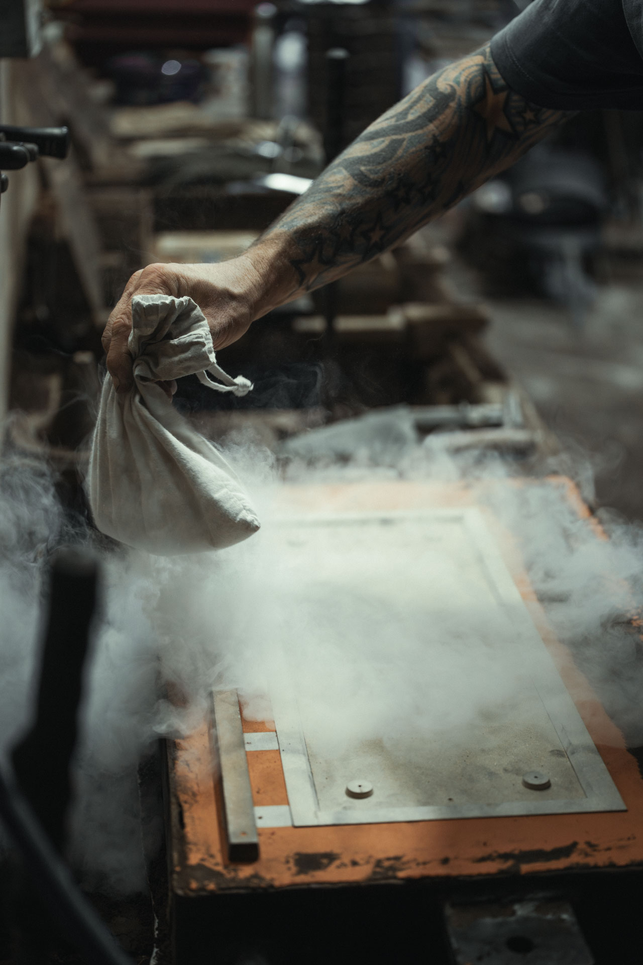 Applying parting powder to a sand mould during the traditional metal casting process in the Anglia Sign Casting foundry workshop.