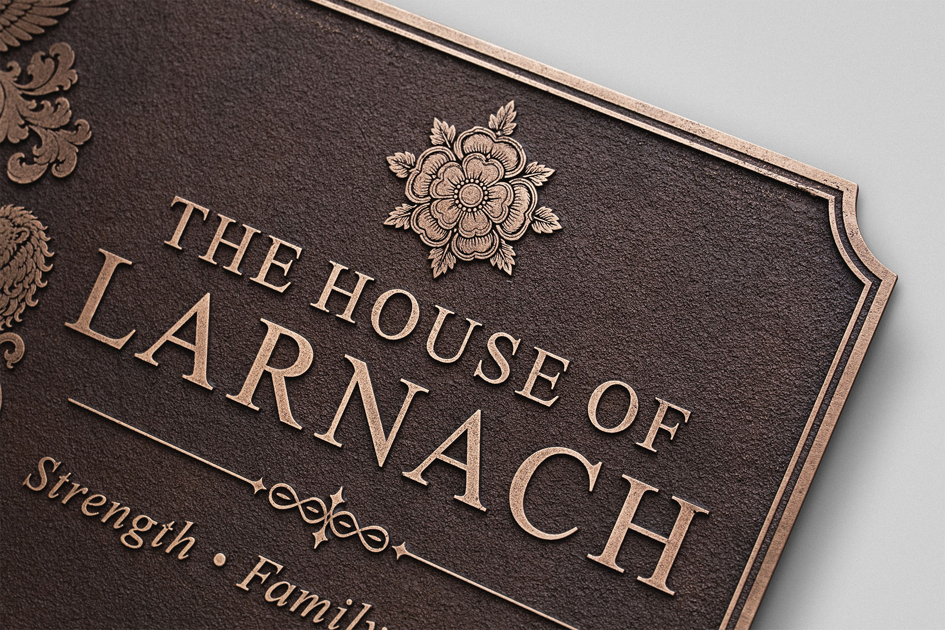 Close-up of raised House of Larnach lettering and decorative rose on a traditional antique finish cast bronze plaque.