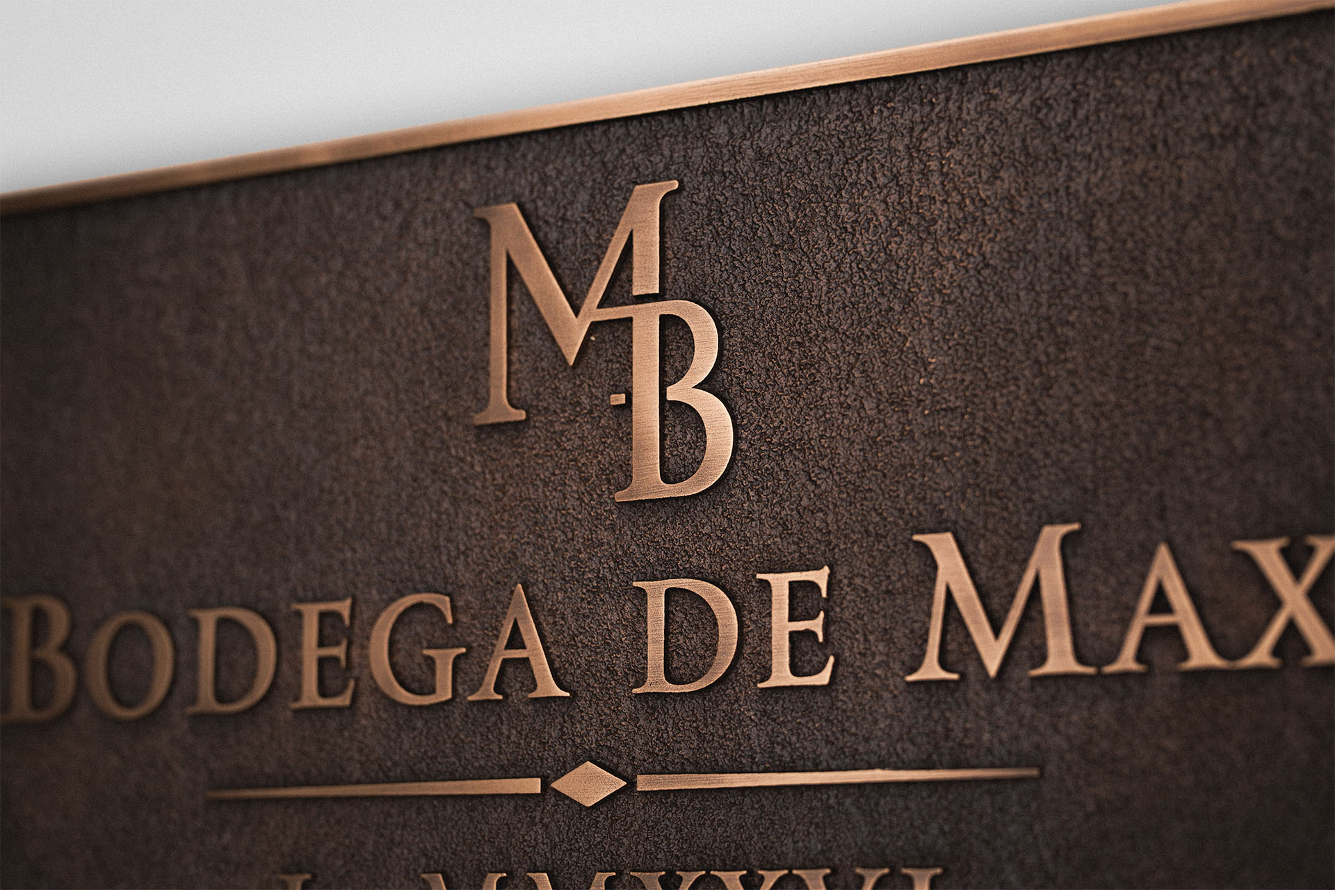 Hand-finished cast bronze plaque showing crisp raised lettering, monogram detail and contrasting dark patina.