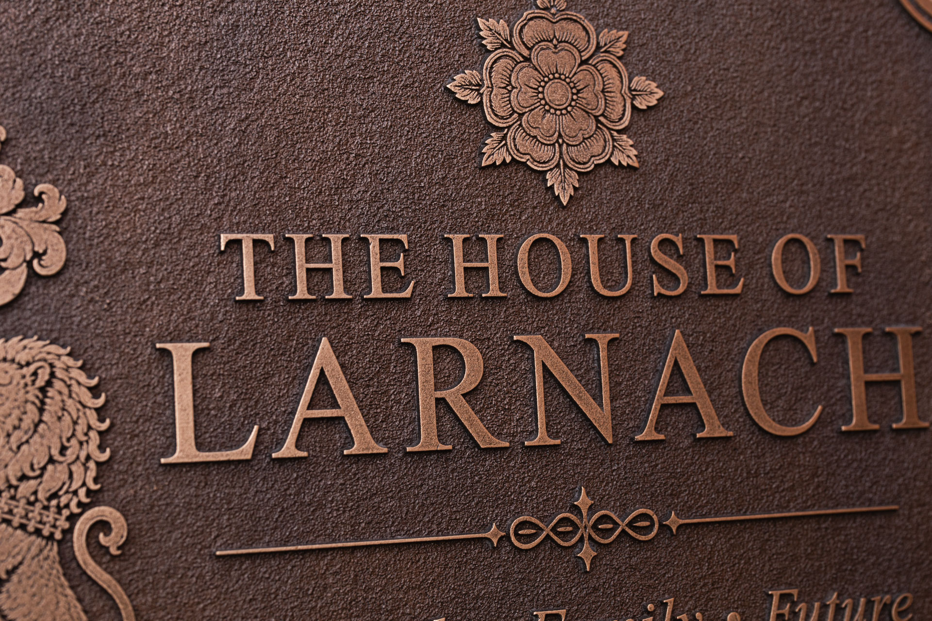 Close-up of a bespoke cast bronze House of Larnach plaque showing raised lettering and detailed rose motif