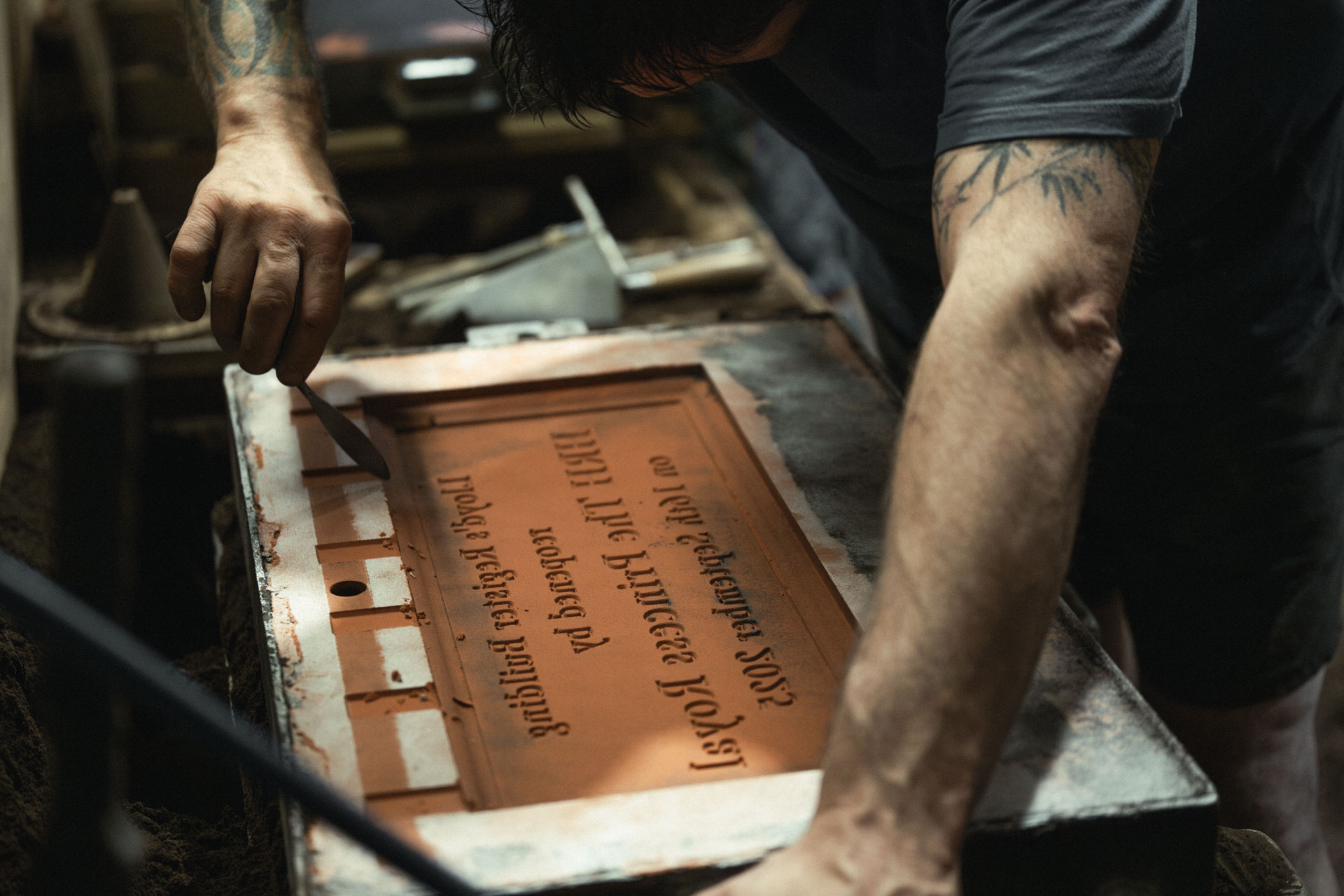 Craftsman carefully tidying and refining a sand mould by hand before casting a bespoke bronze plaque.