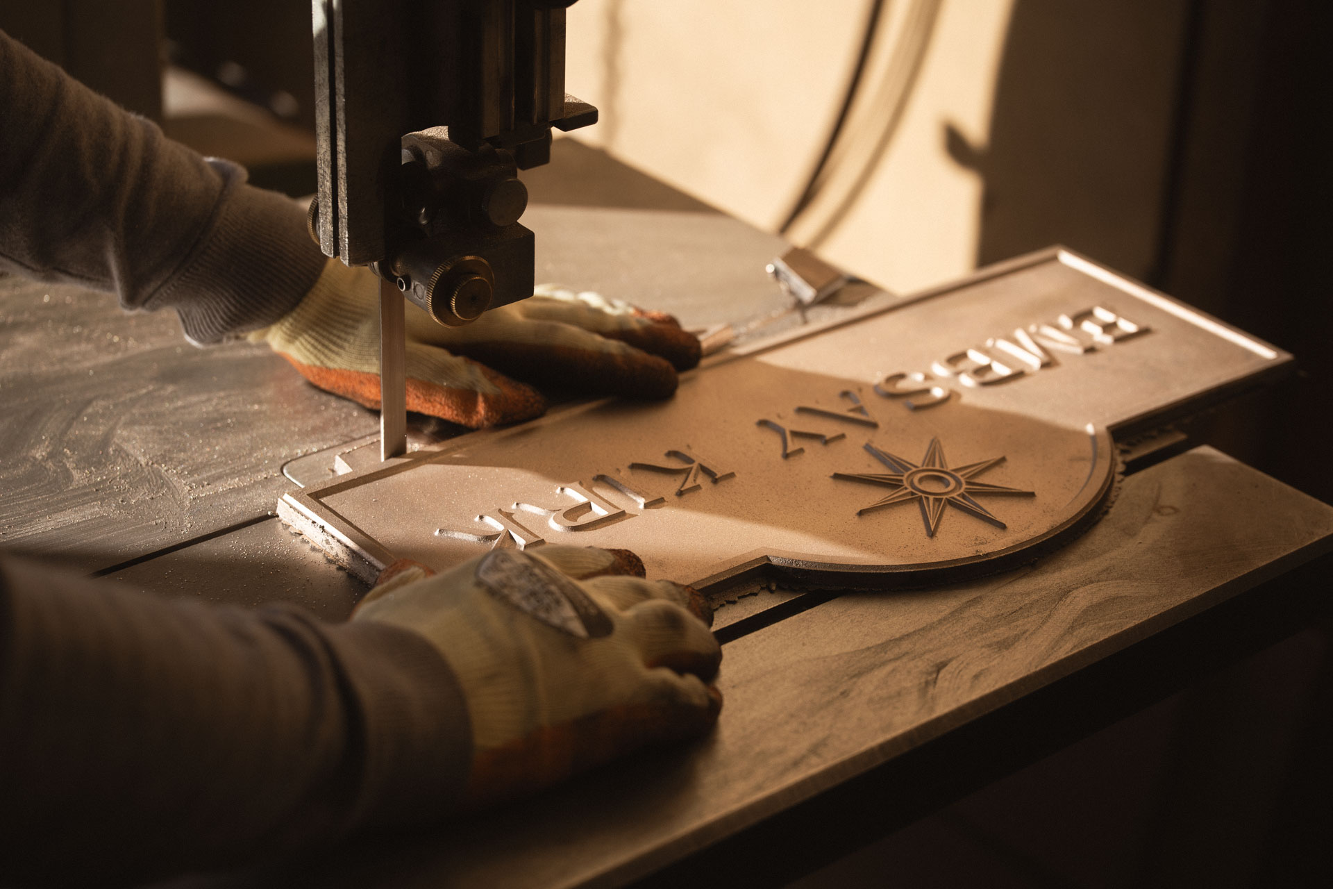 Craftsman cutting the ingates from a rough-cast house sign during fettling, part of the handmade process behind Anglia Sign Casting’s timeless house signs.
