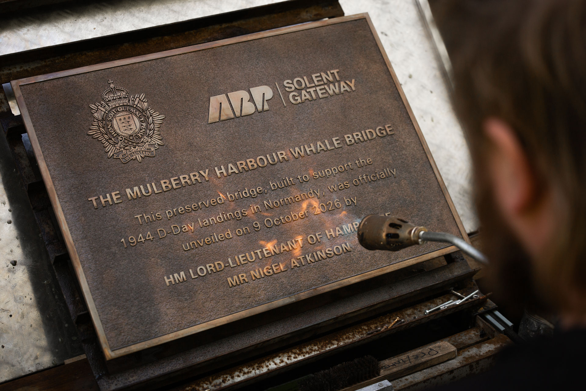 Craftsman applying a traditional patina by hand to a cast bronze commemorative plaque.