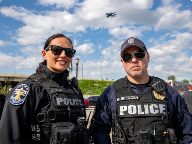Male and female police officers standing outside on a sunny day wearing sunglasses and their police gear