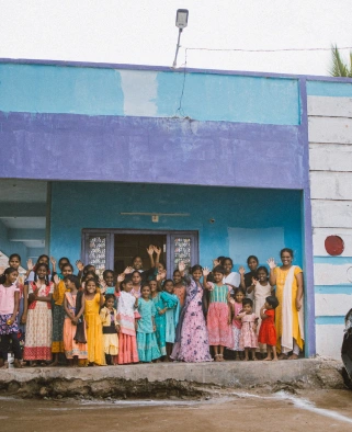 Joyful children standing outside a safe home built by Angel House