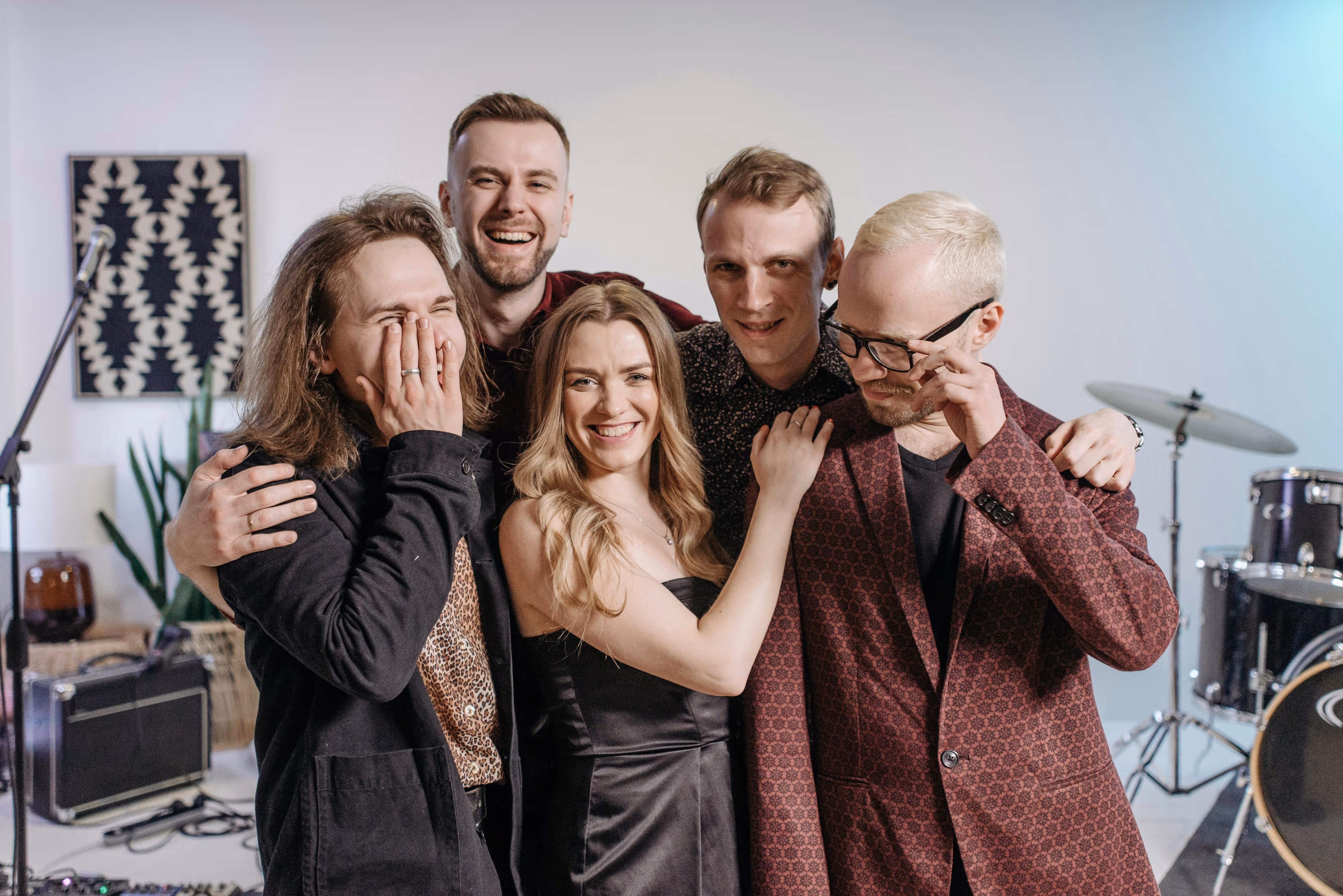 A group of musicians hugging while smiling and laughing.