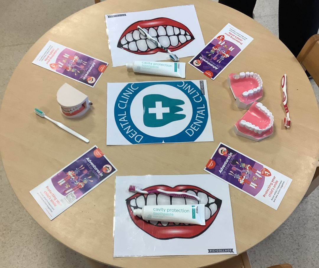 Round table display with dental health educational materials including toothbrushes, toothpaste tubes labeled cavity protection, dental models, and brochures titled Adventures in the Molars West.