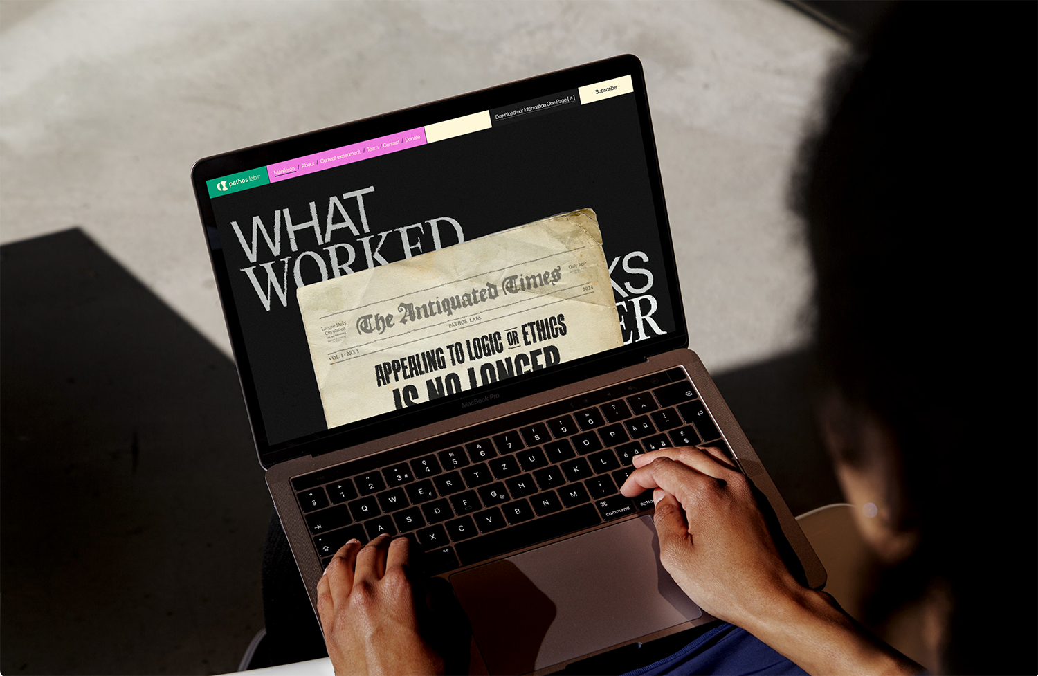 A person is looking up at a computer displaying the introduction to Pathos Labs' website.