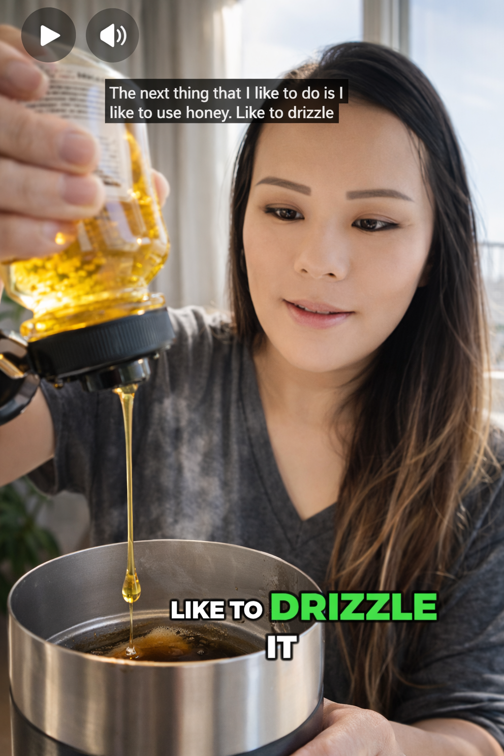 Woman drizzling golden honey from a squeeze bottle into a stainless steel milk frother filled with coffee, with visible honey stream and soft natural window light creating a warm, cozy kitchen atmosphere.