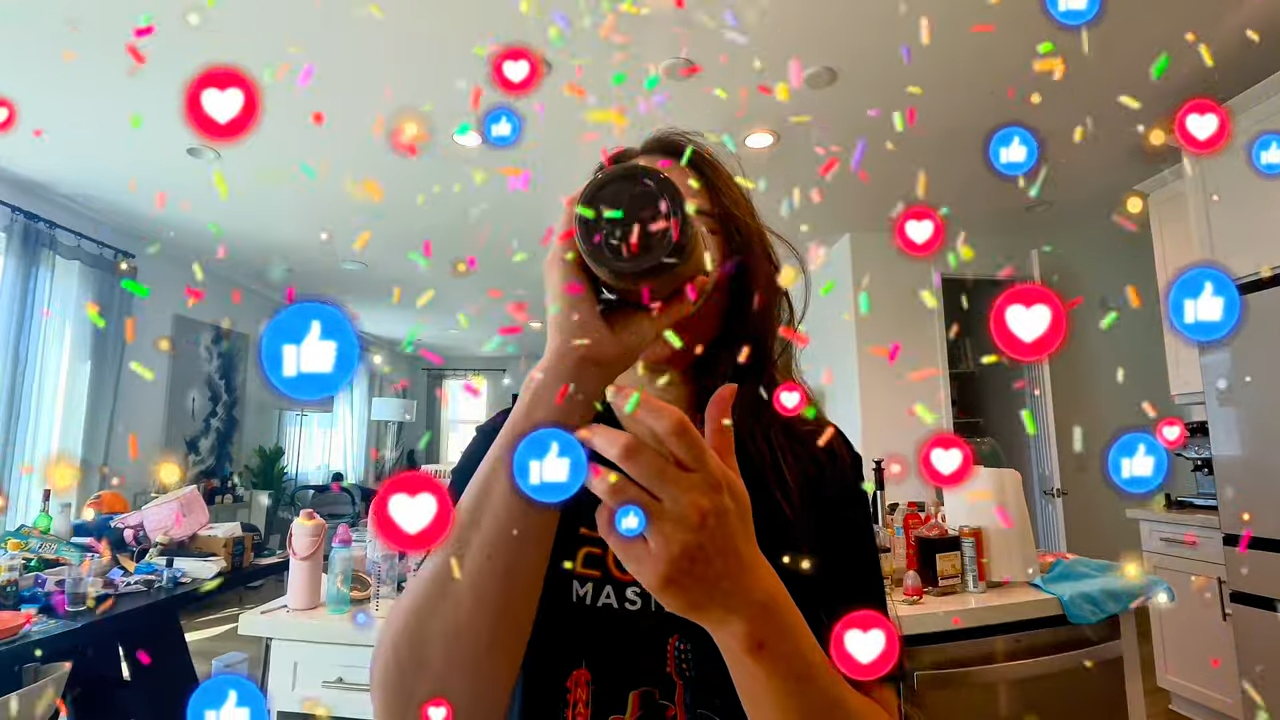 Young woman drinking from a tumbler while surrounded by colorful confetti and floating social media heart and like icons in a bright modern kitchen with a fun celebratory aesthetic.
