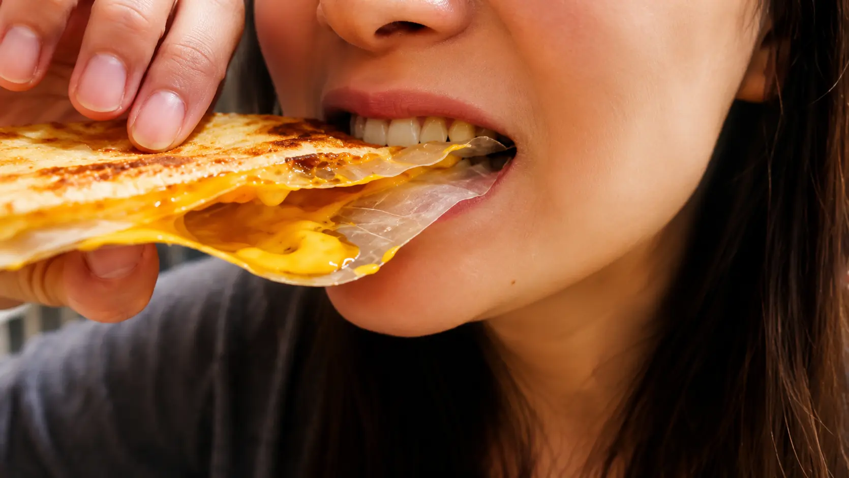 Extreme close-up of a woman taking a bite of a crispy Vietnamese rice paper pizza filled with melted cheese. The golden-brown rice paper has a crunchy, blistered surface, while gooey cheese stretches from the center and peeks out from the edges. The focus is on the rich textures of the crispy rice paper, creamy cheese, and satisfying bite, creating a mouthwatering food-photography scene with a soft, blurred background.