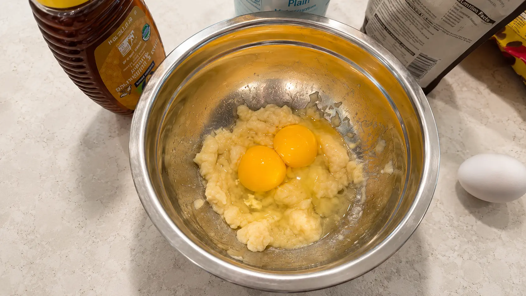 Eggs and mashed banana combined in a bowl for flourless high protein brownies. Eggs provide protein while helping create a rich and fudgy brownie texture.
