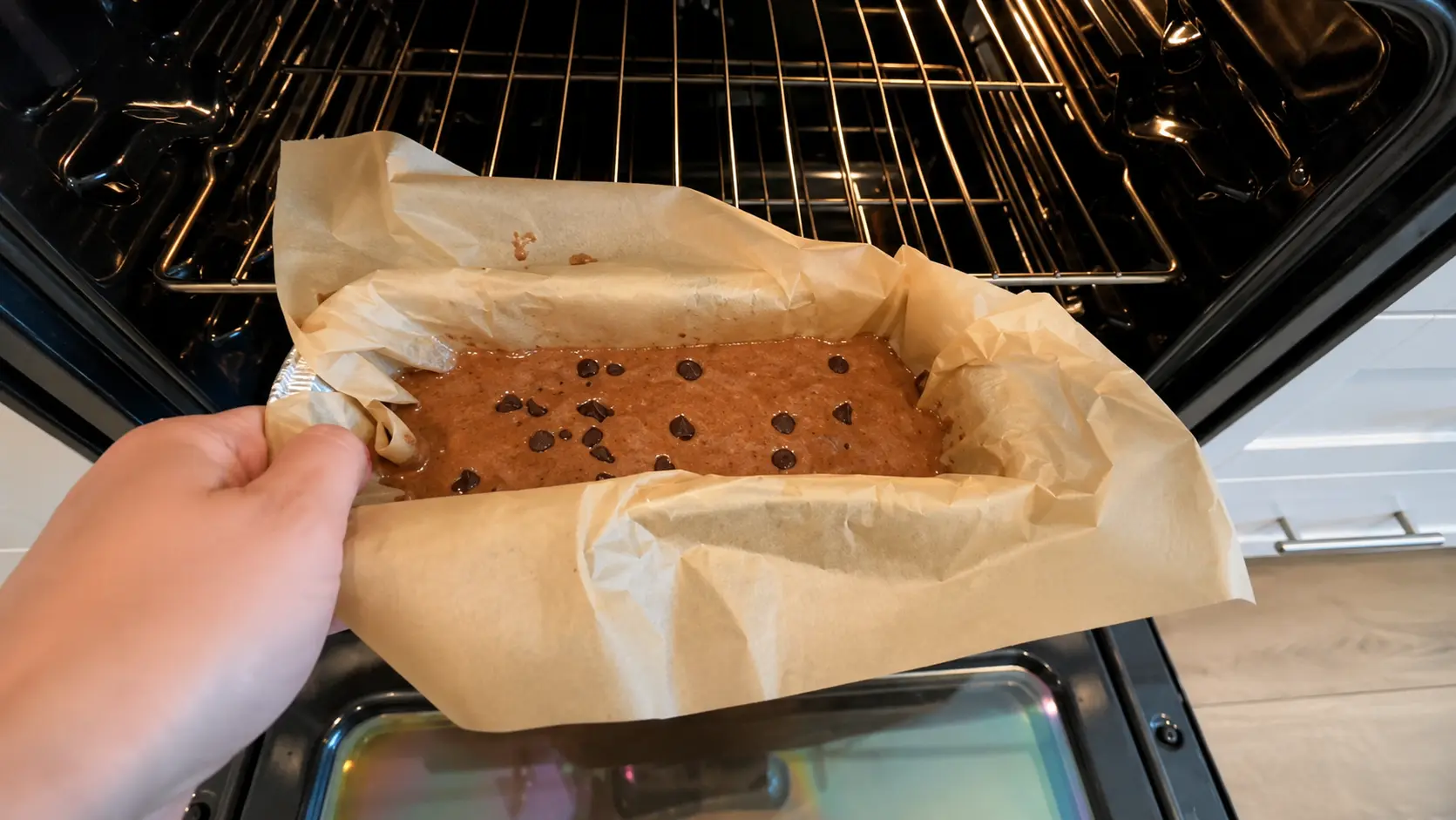 Baking flourless high protein brownies in the oven. The chocolate brownie batter is topped with chocolate chips and prepared to bake at 350Β°F.