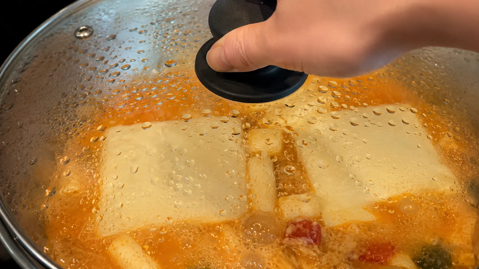 **Alt text:** **Glass lid covering cheesy Shin ramen noodles as white American cheese melts into a creamy spicy broth.**