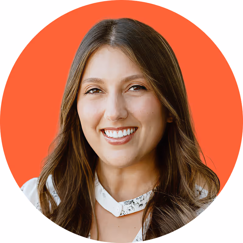 Smiling man with short black hair wearing a white shirt and black blazer against an orange background.