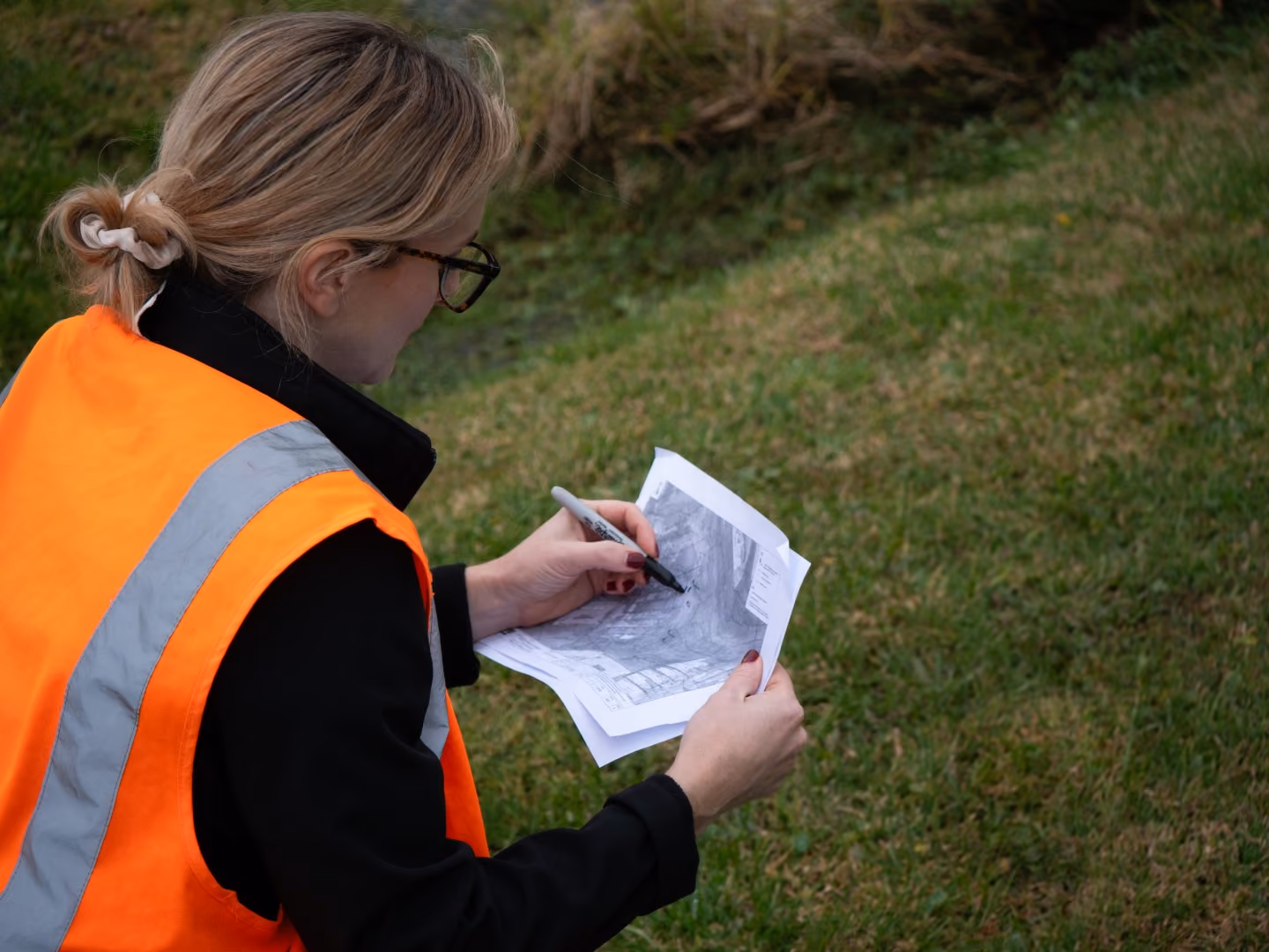 An environmental scientist on-site reviewing a map of assessment and analysis sites to conduct an assessment to support ongoing projects