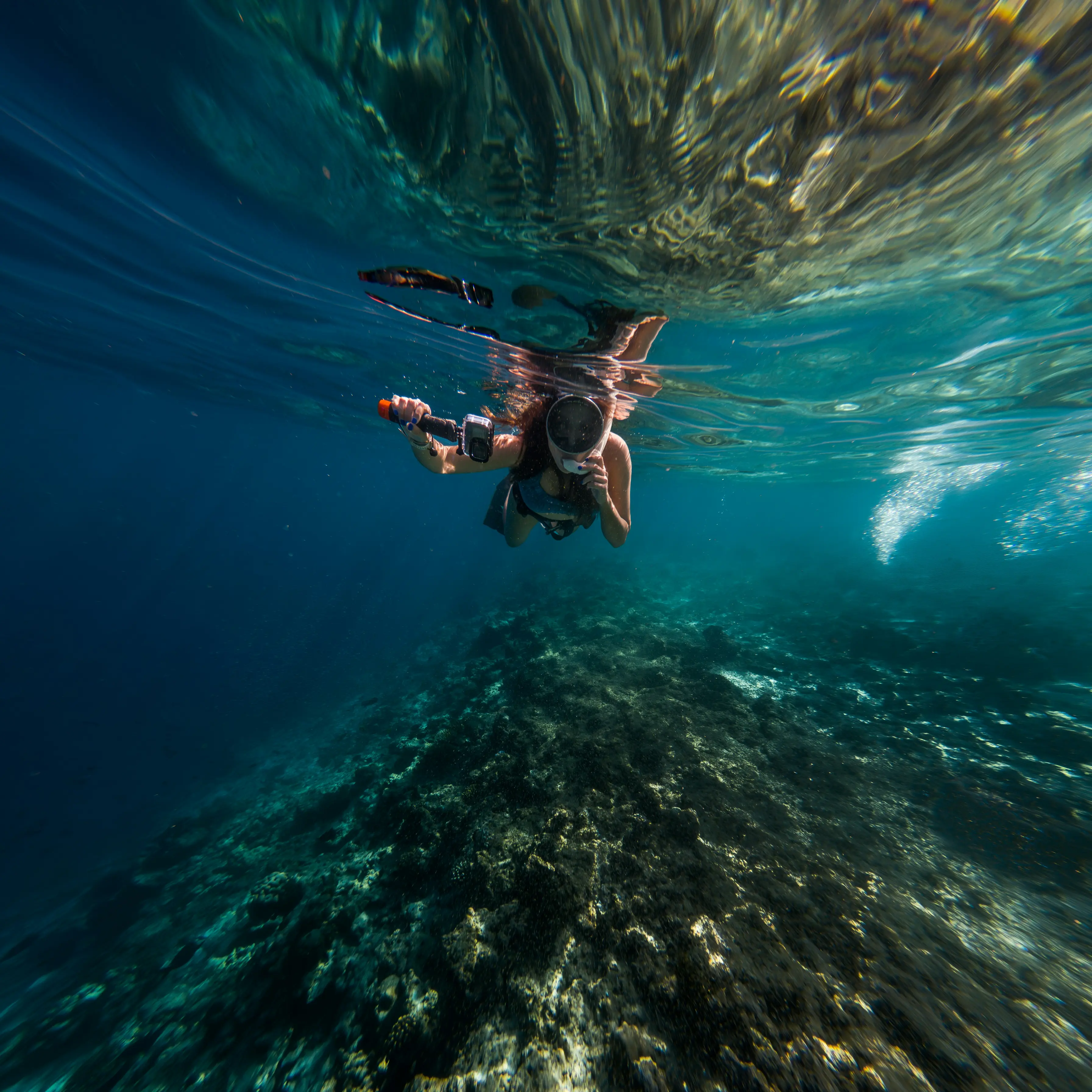 a girl snorkeling in a cristal clear blue water